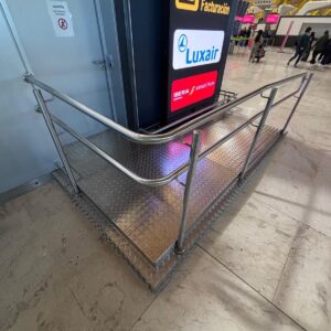 Barandillas y rampas de acero inoxidable instaladas en terminal de aeropuerto para mejorar accesibilidad